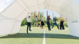 Teammembers jumping under scissor structure tent