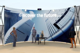 People in front of Curved structure with screen as exhibition stand