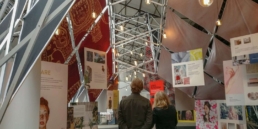 People looking at scissor strucutre exhibition booth.